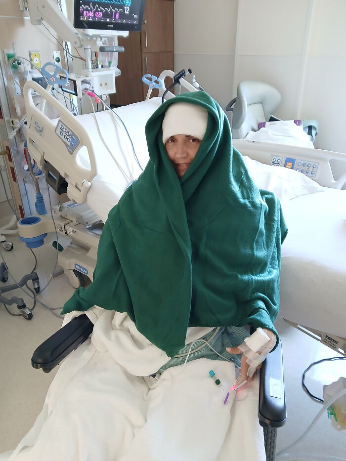 Paralyzed woman in hospital bed wrapped in green blanket demonstrating Elon Musk Neuralink brain chip technology. - 3