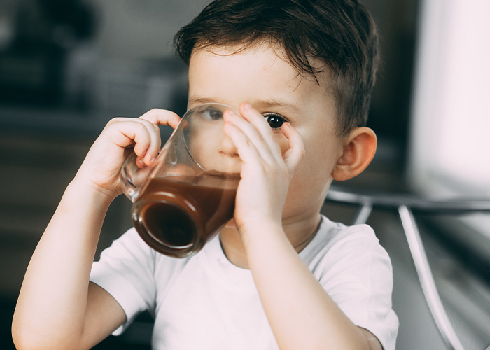 Young boy drinking chocolate milk, illustrating parents reveal hilarious lies they tell their kids about food and drinks.