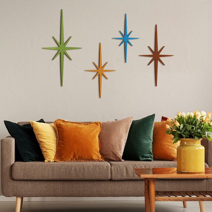 Retro finds featuring a cozy sofa with colorful pillows and mid-century starburst wall decor in a vintage living room.