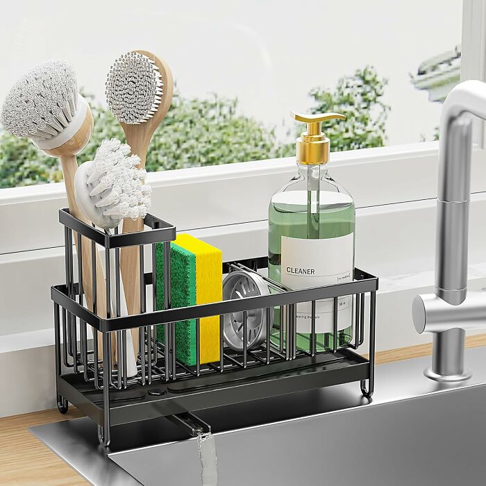Black kitchen sink organizer with brushes, sponge, and soap dispenser drying by the window, popular Amazon item.