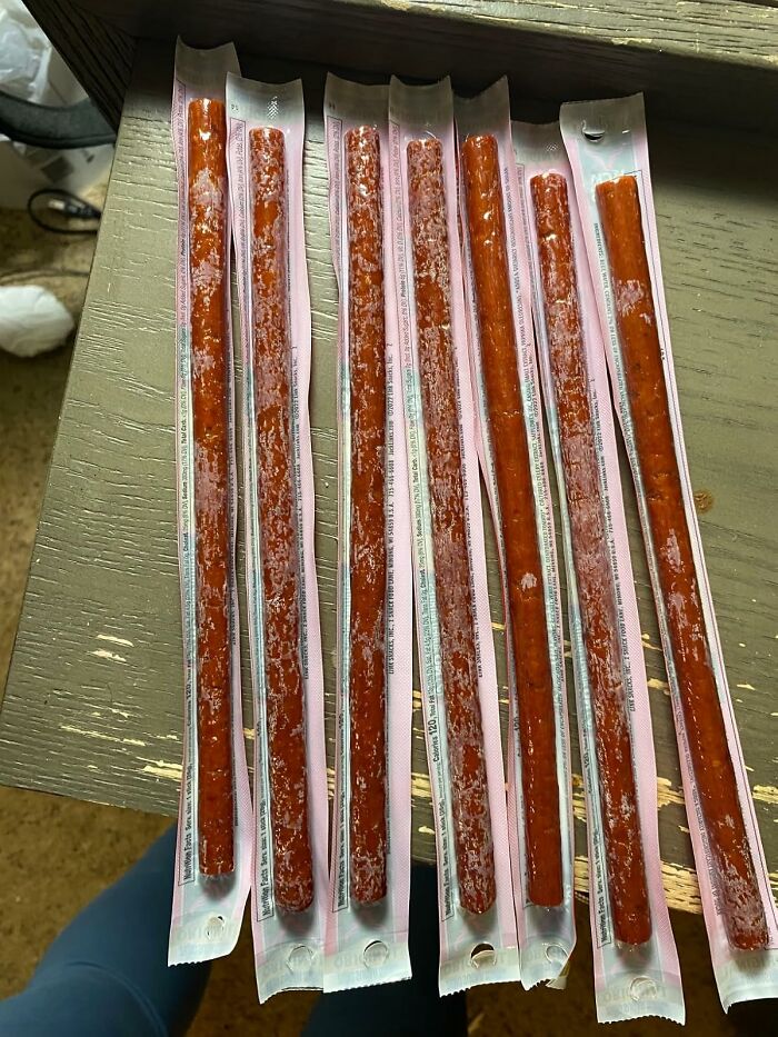 Eight individually wrapped beef sticks arranged on a wooden surface, showcasing Prime Day treasures snack options.