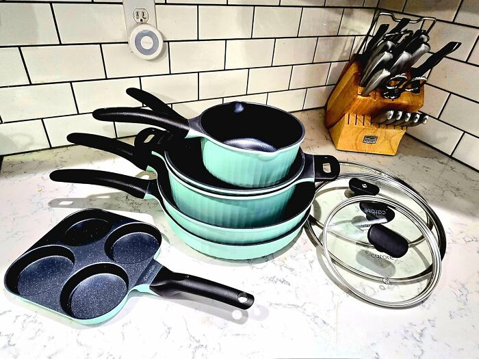 Stack of teal nonstick cookware including pans, pots, and lids on a kitchen countertop, best sellers that topped the charts.