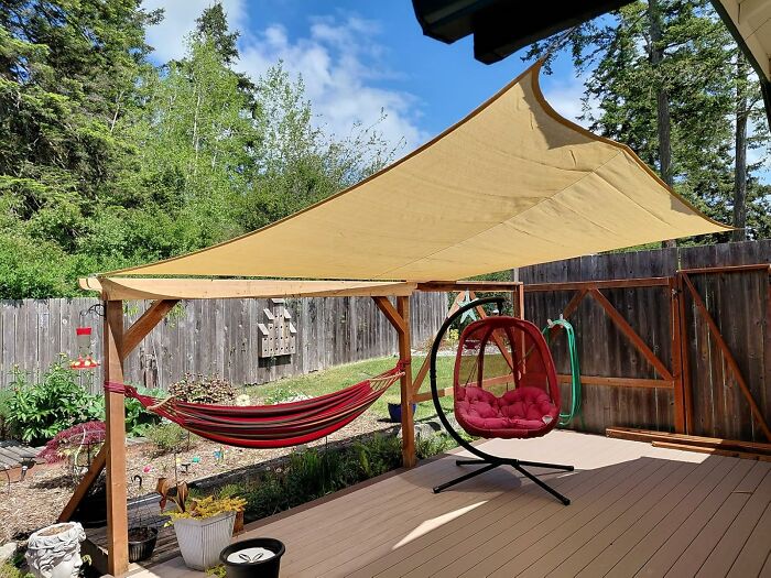 Backyard patio with shade sail, hammock, and hanging chair, illustrating heatwave hacks for summer survival.