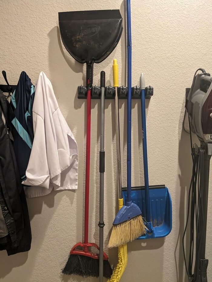 Organized cleaning tools hanging neatly on wall hooks as a clever home hacks starter pack for life together.