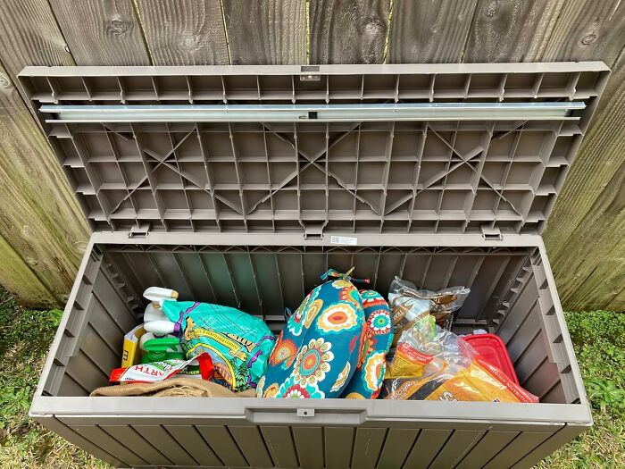 Outdoor storage box filled with colorful bags and cleaning supplies, a clever product to organize chaotic corners of your home.