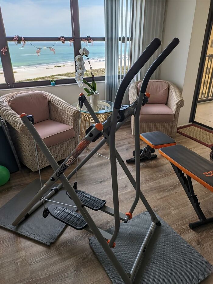 Elliptical exercise machine and workout bench in a bright room with ocean view, an infomercial fitness find.
