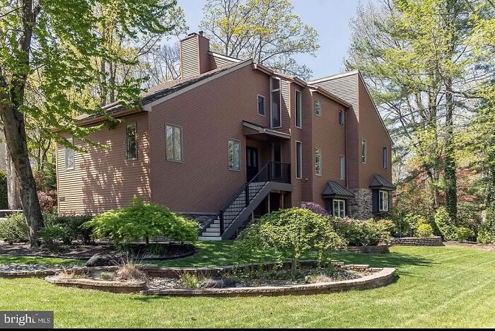 Modern brown house with stairs and an irregular design among trees in a suburban setting showing creative home ideas.