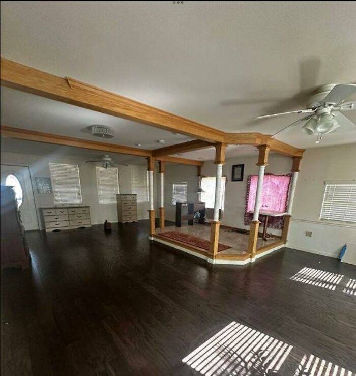 Open living space with dark wood floors and an unusual wooden column structure, showcasing a creative home design fail.