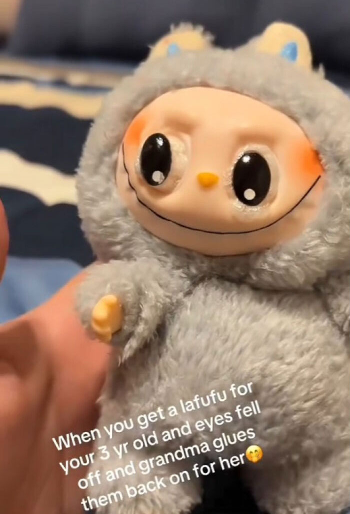 Creepy Labubus doll with large eyes and fuzzy outfit held in hand, showcasing unsettling fake toy design.