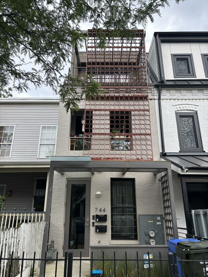 Front view of a home with a creatively failed metal circle facade covering windows and balcony area.