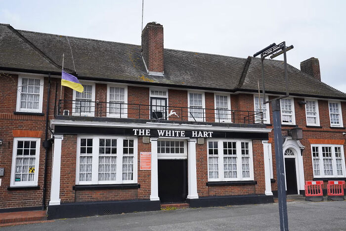 The White Hart pub building with a Ukrainian flag at half-mast, representing job loss consequences and workplace issues.