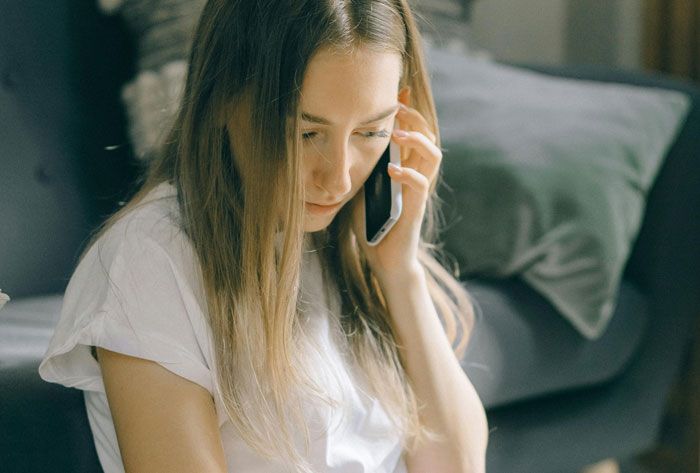 Girl survives cancer, speaking on phone, reflecting and accepting prosthetic leg with brother's support at home.