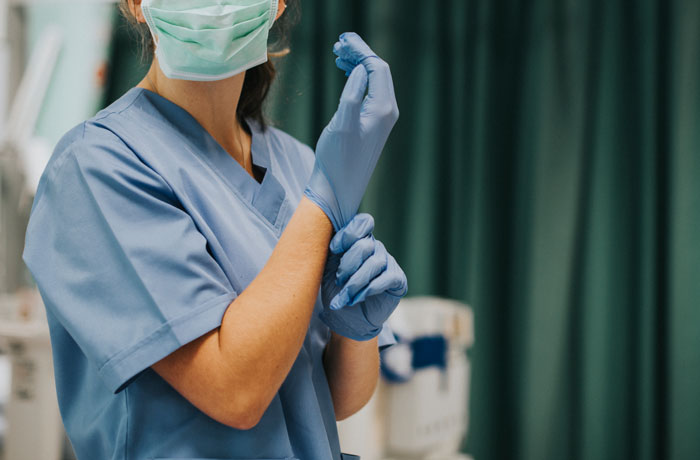 Personal médico en hospital colocándose guantes antes de atender pacientes para evitar errores terribles en hospitales.
