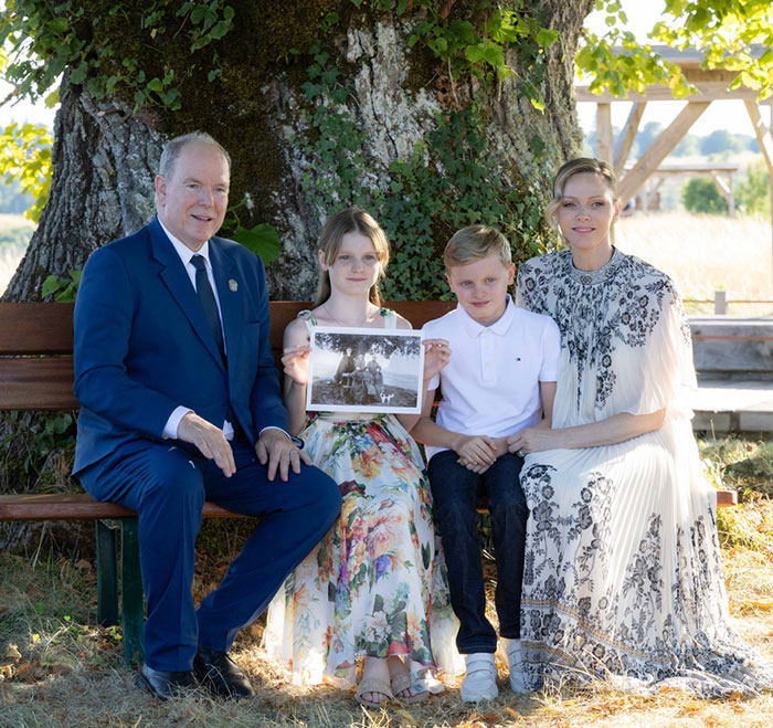 Grace Kelly&rsquo;s granddaughter wearing a timeless dress, seated with family outdoors at a charity event.