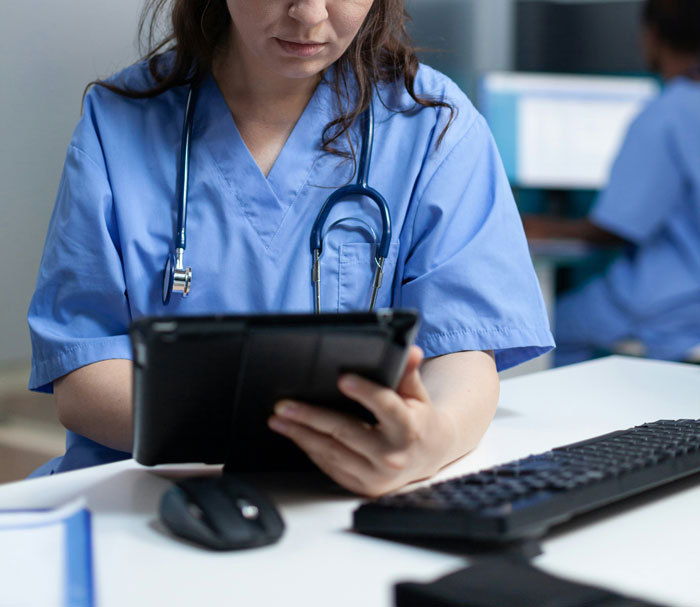 Medical professional in blue scrubs using a tablet, highlighting concerns about lack of respect for patients’ privacy. - 24