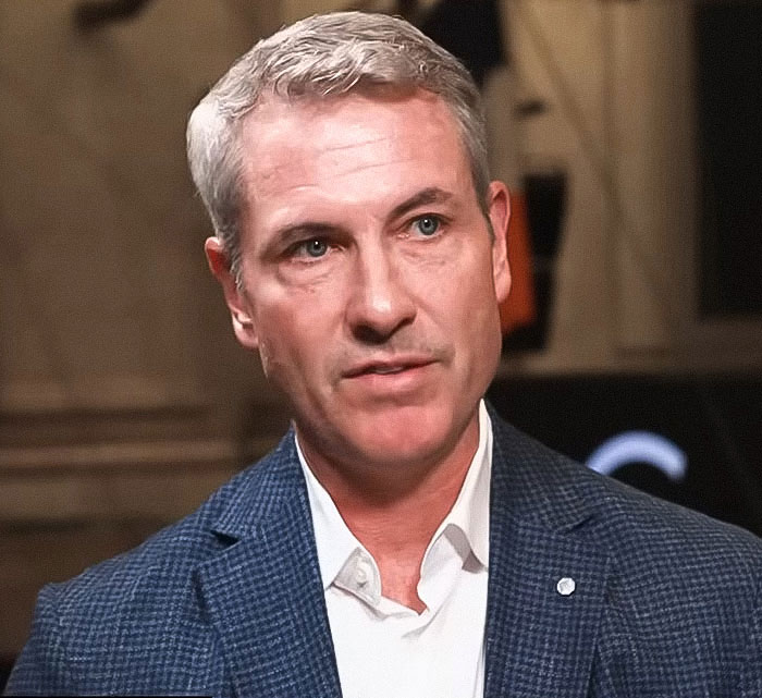Man in a blue blazer and white shirt appearing serious during an interview about the viral Kiss Cam cheating incident.