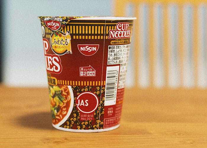 Cup noodles container on a wooden table, illustrating bizarre family habits shared by people as normal experiences.