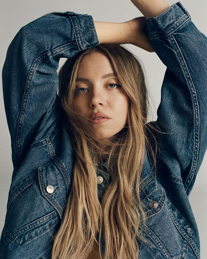 Young woman in a denim jacket posing with arms raised highlighting American Eagle jeans in a fashion portrait. - 2