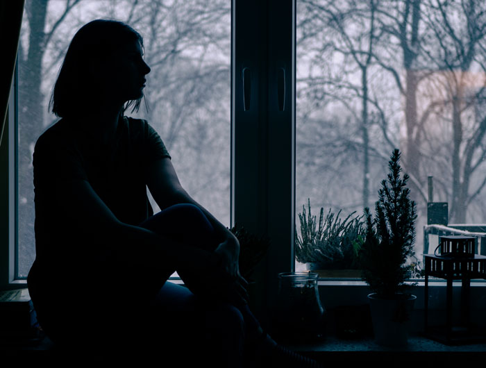 Silhouetted person sitting by a window at dusk, evoking a mood of unexplainable real-life horror stories and suspense. - 2