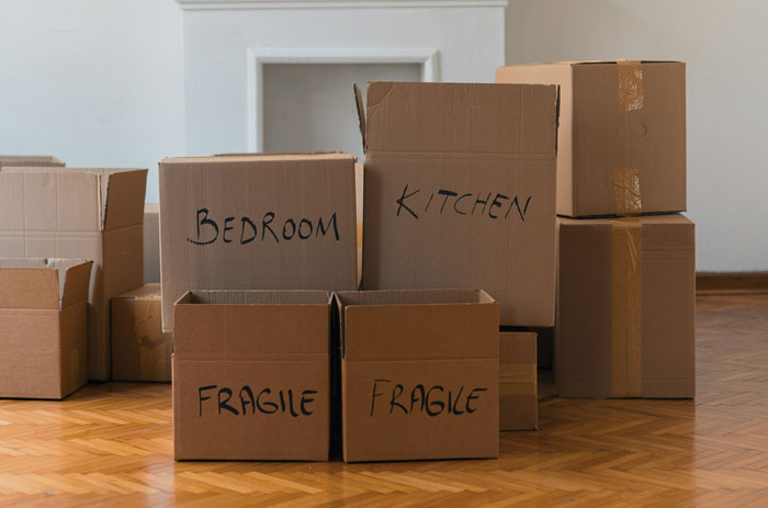 Stack of labeled moving boxes in an empty room representing woman upset about SIL taking her daughter away.