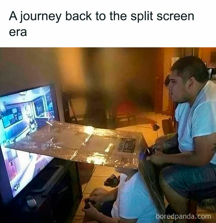 Two men playing video games with a plastic split screen between them, capturing nostalgia of growing up in the ’90s.