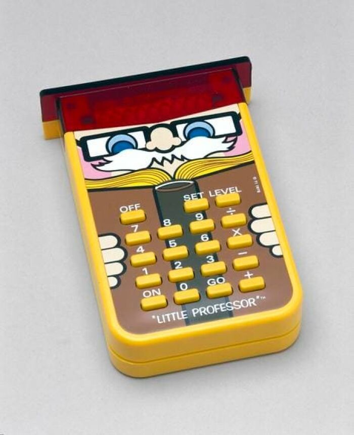 Yellow handheld electronic game called Little Professor with a cartoon professor face, a nostalgic toy from the 90s childhood.