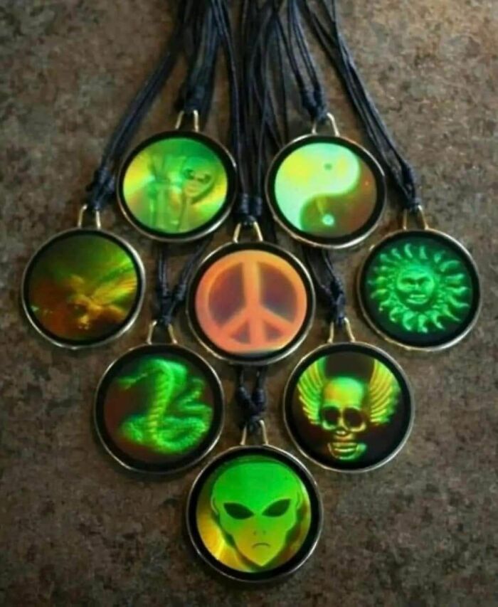 Holographic pendants featuring 90s nostalgic designs like peace sign, alien, skull with wings, and yin yang on black cords.
