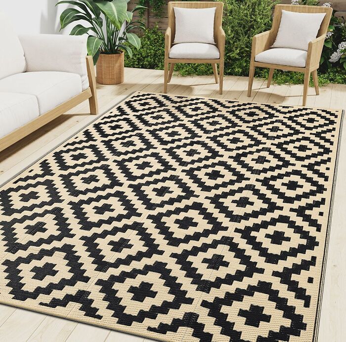 Outdoor seating area with geometric patterned rug, wooden chairs, sofa, and potted plants for Prime Day treasures.