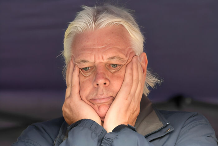 Middle-aged man with white hair holding his face, showing regret and stress related to consequences of job loss.