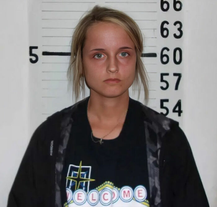 Young woman in front of height chart, representing consequences of stupidity leading to job loss and legal trouble.