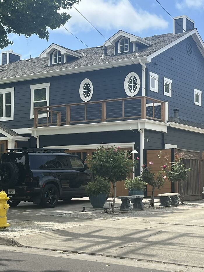 Modern dark blue house with unusual oval windows and balcony railing, showcasing people creative home design fails.