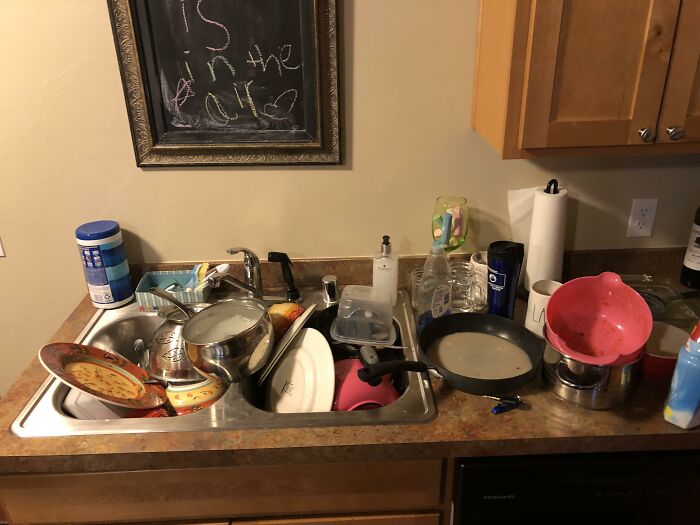 Messy kitchen sink filled with dirty dishes and cookware showing typical roommate challenges in shared living spaces.