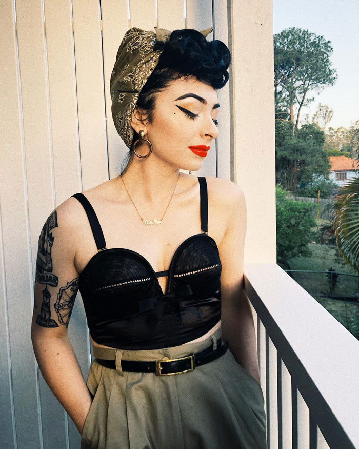 Woman with tattoos on arm wearing vintage headscarf and black top, showing body suit tattoo transformation. - 1