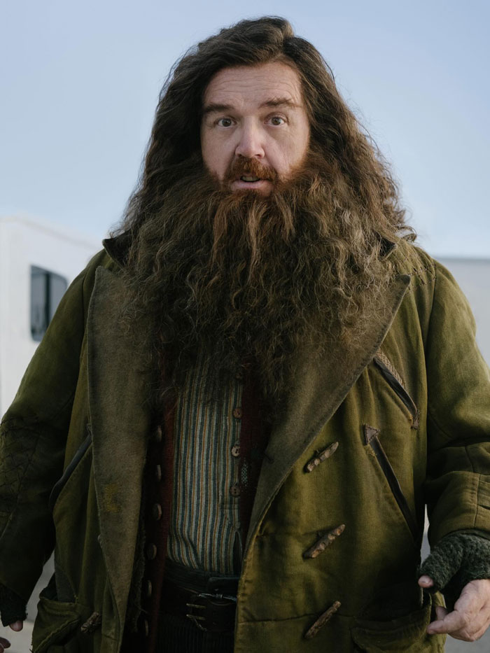 Actor in character as Hagrid with long hair and beard wearing a rugged coat, sparking Harry Potter fans' reactions to his first look.