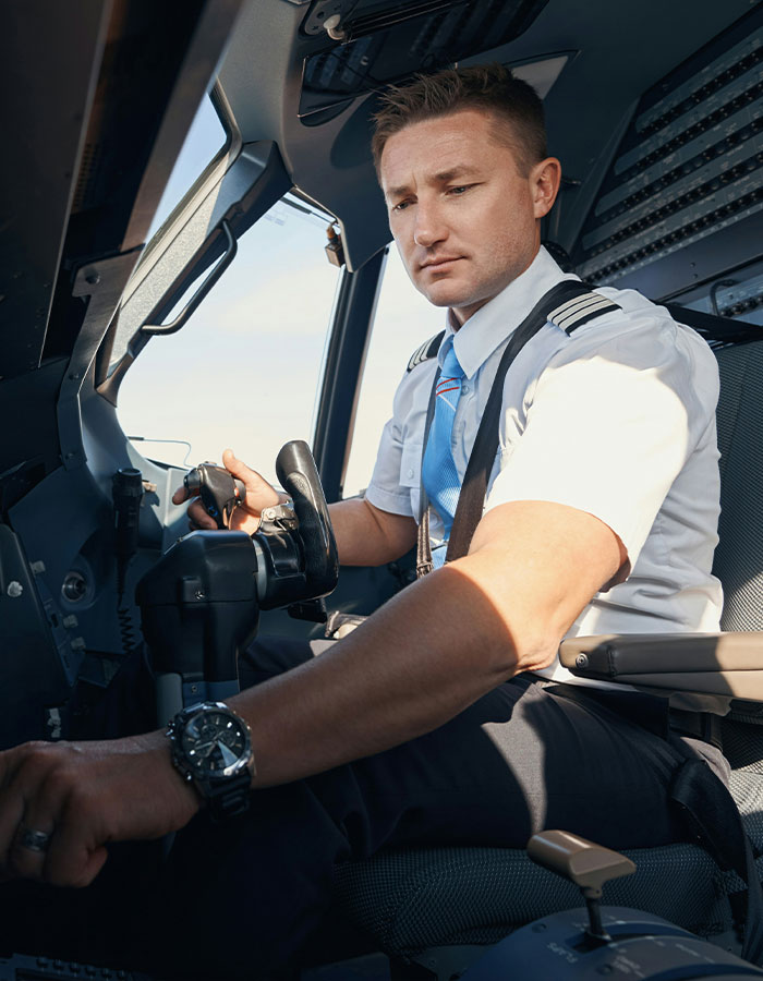 Pilot in uniform operating controls inside the cockpit during flight amid passenger scare causing emergency landing.