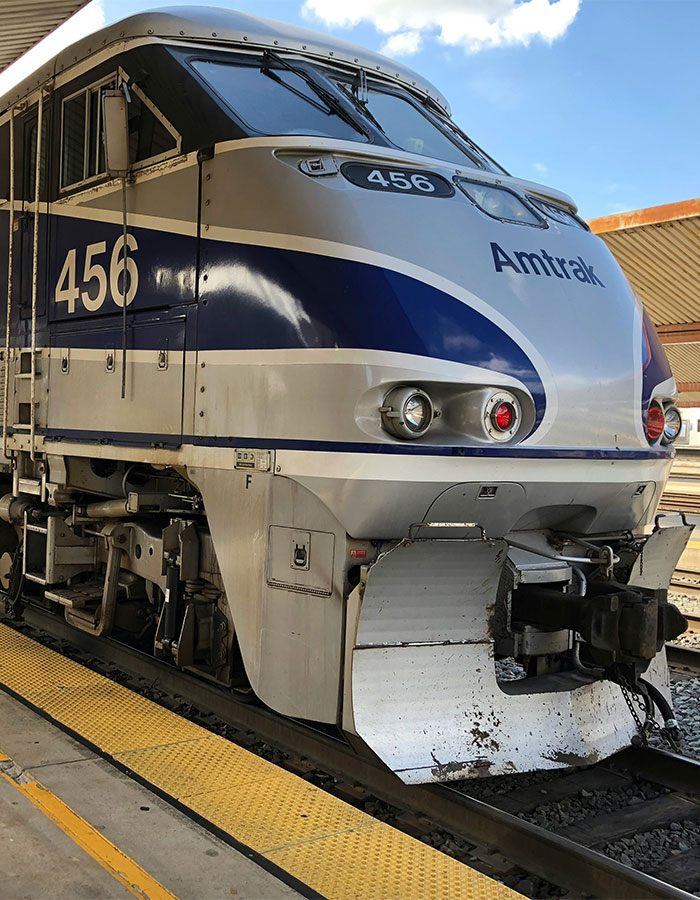 Amtrak train 456 standing at station platform under blue sky during daytime travel scene.