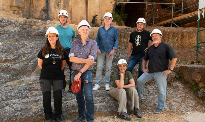 Group of archaeologists wearing helmets at an excavation site discovering evidence of prehistoric ancestors eating toddlers.