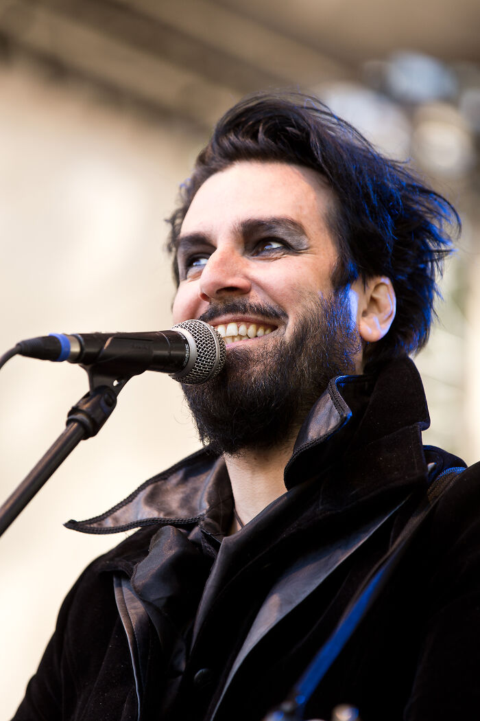Man with dark makeup and beard speaking into microphone, symbolizing revenge on bosses in a bold confident style. - 28