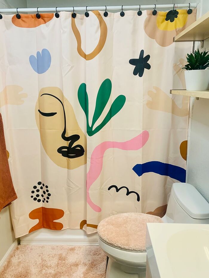 Bathroom with colorful abstract shower curtain and soft rugs showcasing fun home decor ideas.