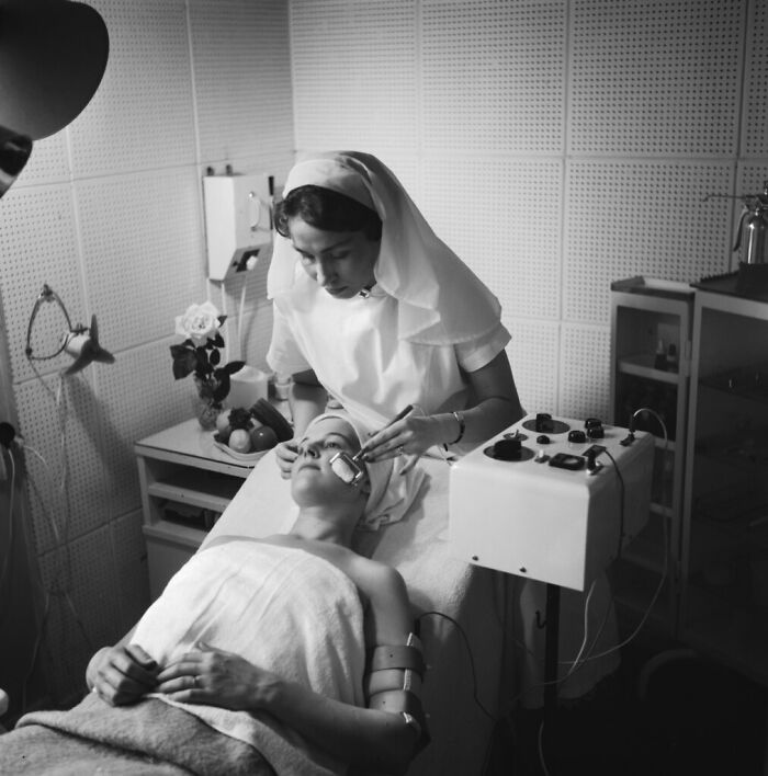 Black and white photo of a nurse administering early medical treatment in a rare and interesting historical photograph.