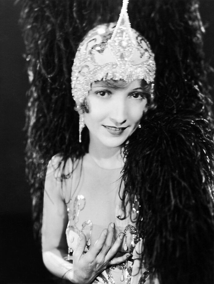 Vintage portrait of a woman wearing a beaded headdress and feathered costume showcasing timeless beauty and elegance.