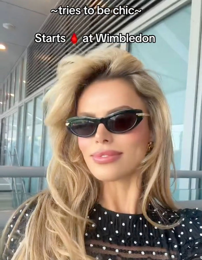 Brooks Nader wearing sunglasses and a black polka dot top, praised for normalizing period leaks and women&rsquo;s health.