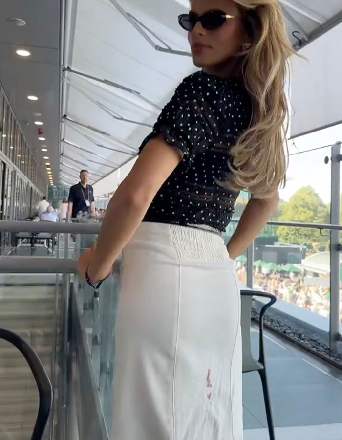 Brooks Nader wearing sunglasses and a white skirt with a visible period leak, normalizing period leaks for women.