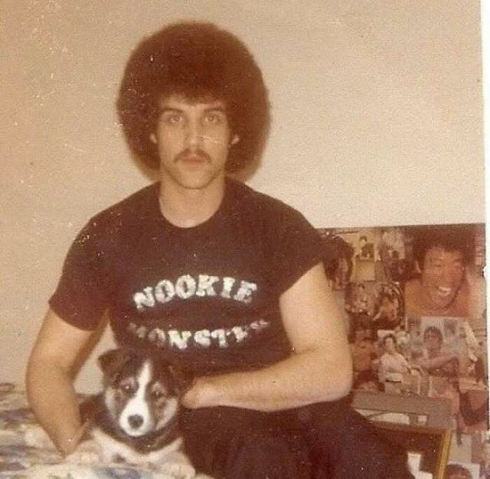 Vintage photo of a dad with an afro hairstyle wearing a Nookie Monster shirt sitting with a dog, showcasing old school cool style.