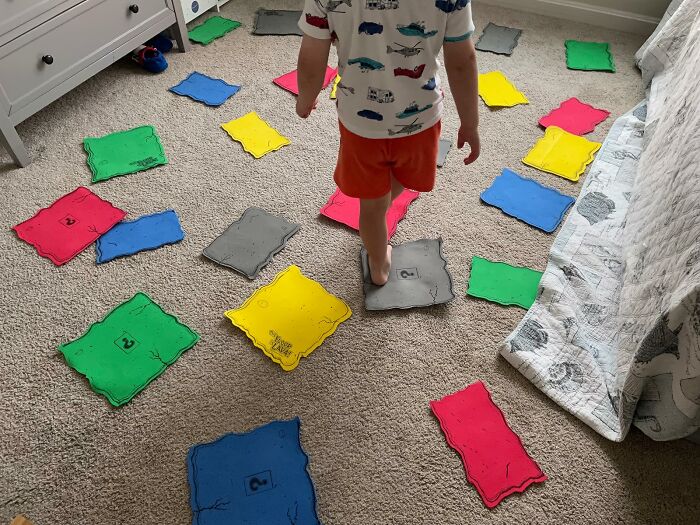 Child playing on colorful toy stepping stones scattered on carpet, showcasing toys under $20 for gifting ideas.