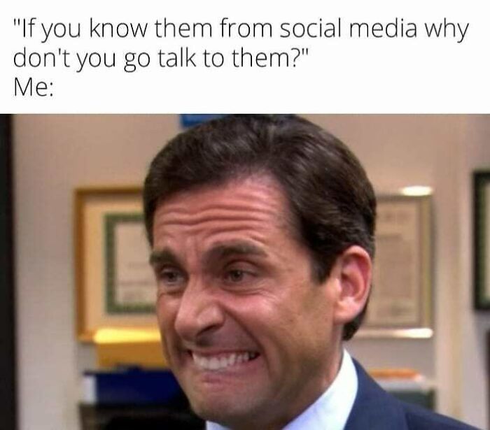 Man grimacing awkwardly in an office setting illustrating social anxiety memes about avoiding social interaction.