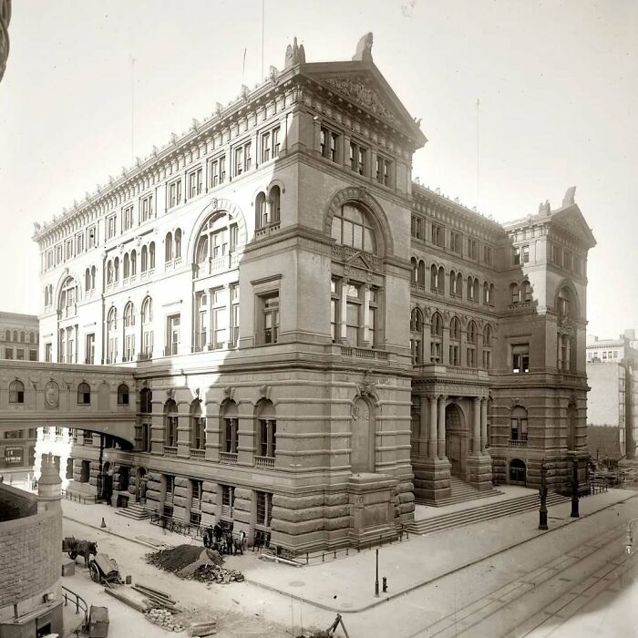 Historic old architecture featuring detailed stonework and arched windows in an urban setting from the past.