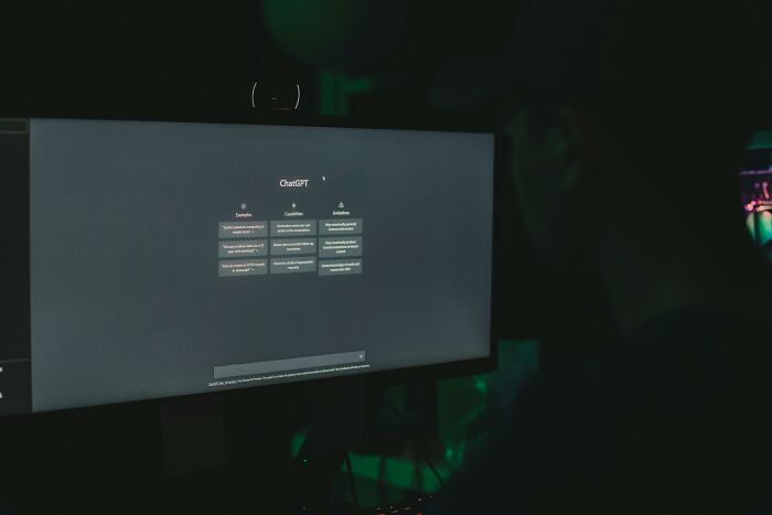 Person using ChatGPT on a dark computer screen, illustrating the impact of AI manipulation and lies on the mind.