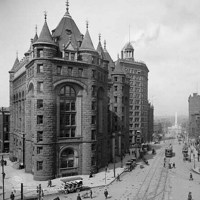 Historic old architecture with intricate stonework and turrets lining a busy early 20th-century city street.