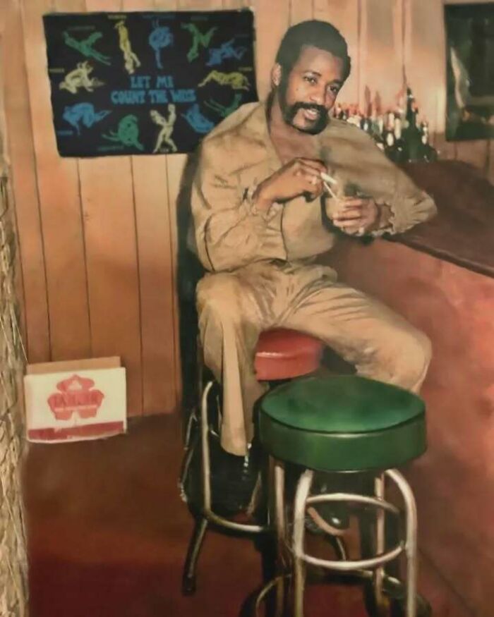 Vintage dad in retro outfit sitting on bar stool, enjoying a drink, exemplifying old school cool style and vibe.